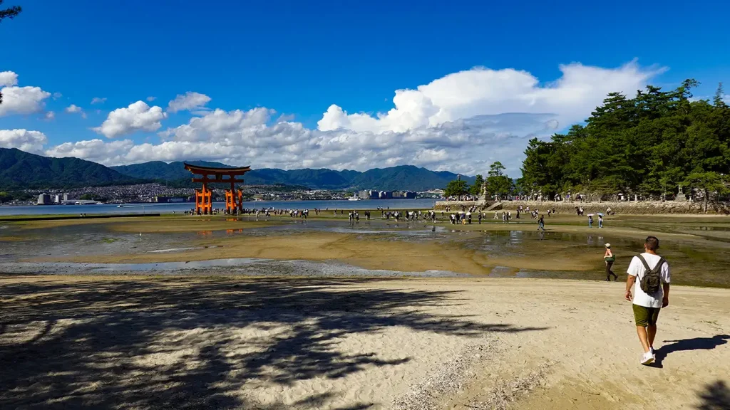 Joan caminando por la arena hacia el gran Torii flotante de Miyajima en marea baja.
