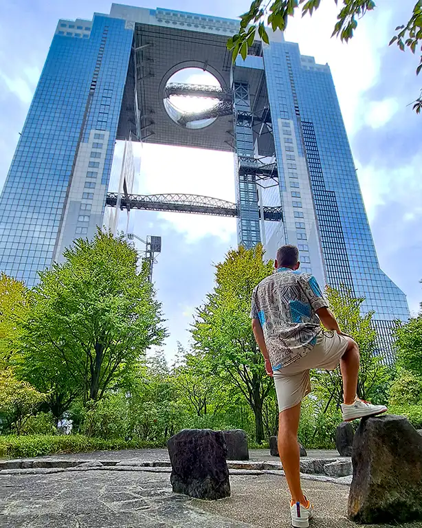 Joan mirando hacia el rascacielos Umeda Sky Building desde un parque.