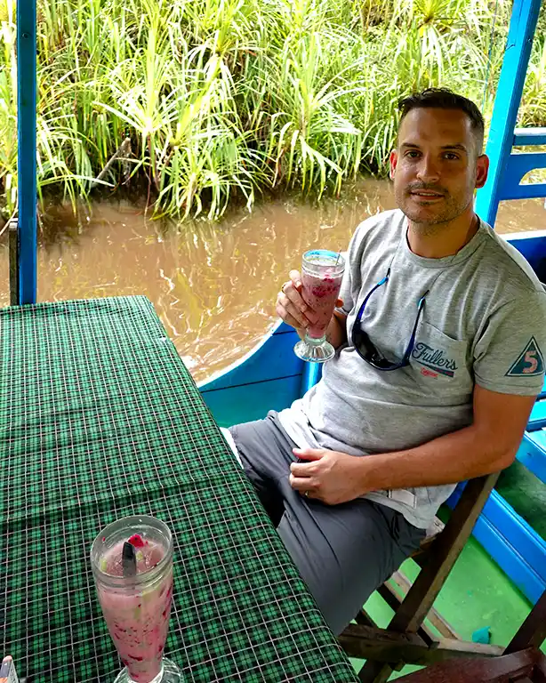 Joan bebiendo un batido tropical a bordo de un barco Klotok en Borneo.