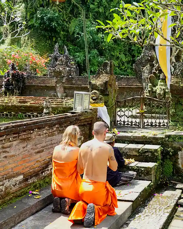 Noelia y Joan recibiendo una ceremonia de purificación de manos de un monje en Bali.