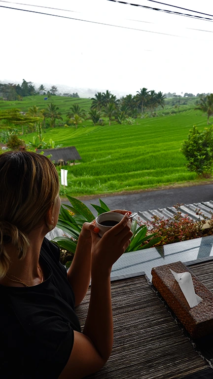 Noelia tomando un café en una terraza con vistas a los arrozales en Bali.