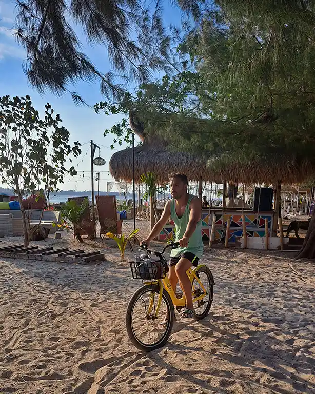 Joan montado en una bicicleta de alquiler por las calles de arena de Gili Air.