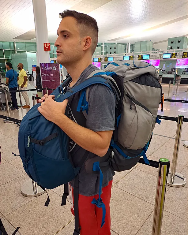 Joan haciendo cola con las mochilas en el mostrador de Qatar Airways.