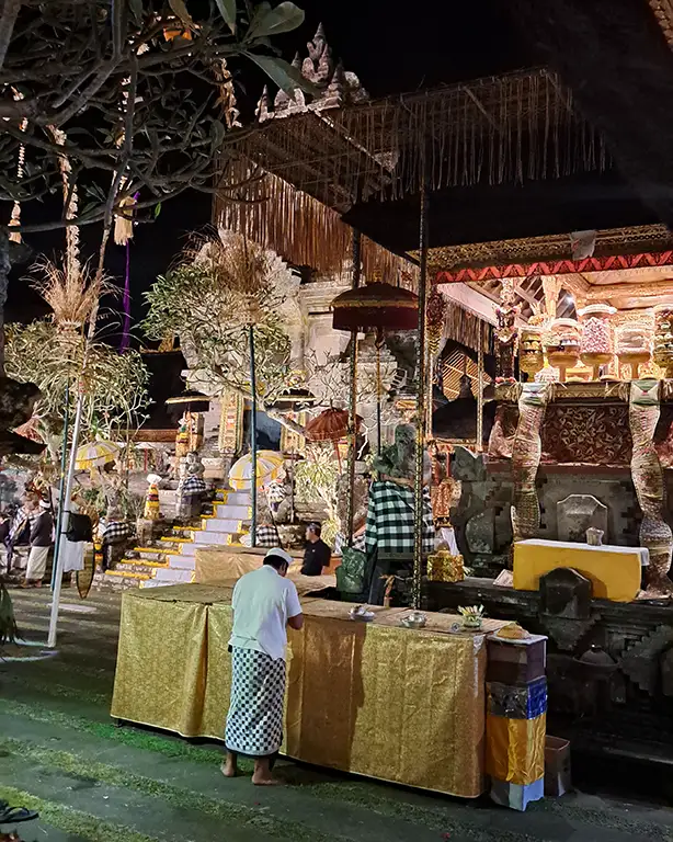 Ofrenda diaria con flores y incienso en el suelo frente a un negocio en Ubud.
