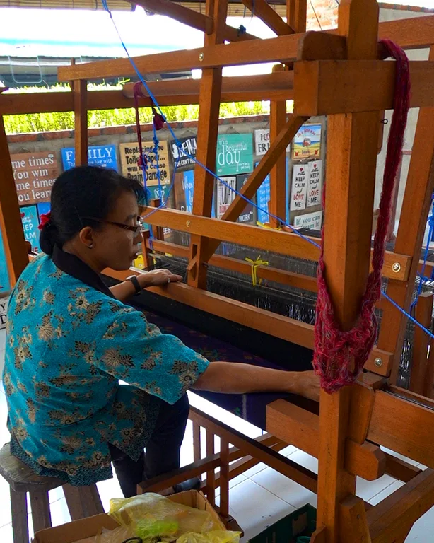 Artesanas locales tejiendo en telares tradicionales en la fábrica de sarongs.