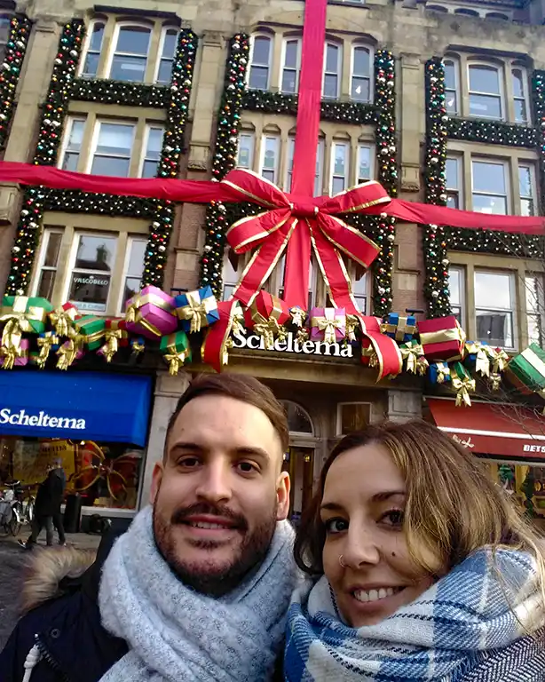 Pareja de viajeros junto a una decoración navideña en Ámsterdam.