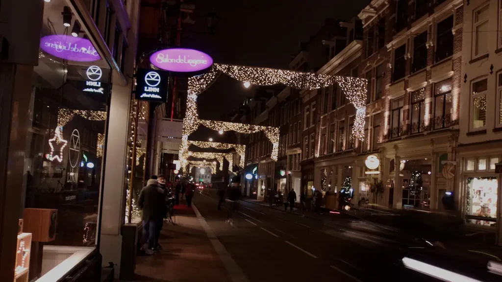 Calle de Ámsterdam con terrazas y decoración navideña de noche.